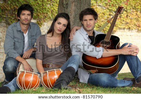 three musicians at the foot of a tree