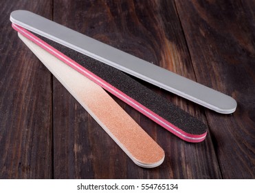 Three nail file with a different abrasive on  dark wooden background