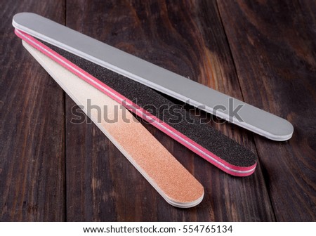 Three nail file with a different abrasive on  dark wooden background