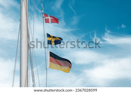 three national flags on the ship's mast: Denmark, Sweden and Germany 