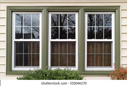 Three new replacement windows with green trim on front of house. Horizontal. - Shutterstock ID 532046170