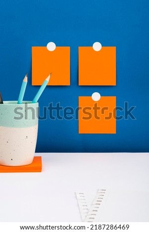Three Notes Sticked On Wall With Important Messages Above Desk With Paper And Cup With Pencils. Crutial Informations Presented On Memos Over Table With Case With Pens.
