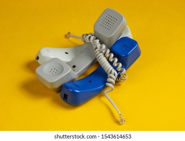 Three Office Phone Tubes Wrapped In Cable On Blue Studio Background. Call Center, Hotline Concept