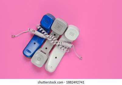 Three Office Phone Tubes Wrapped In Cable On Pink Studio Background. Call Center, Hotline Concept