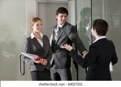 Three Office Workers Chatting At Open Door Of Boardroom