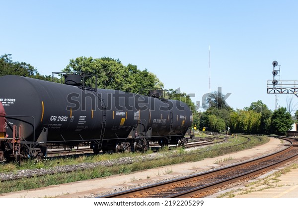 Three oil tanker freight train\
cars are seen together, stationary in a rail yard during the\
day.