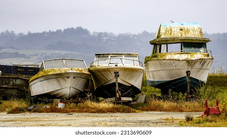 Three old boats being stored on dry land in Moss Landing, CA