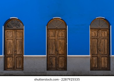 three old wooden doors on blue facade - Shutterstock ID 2287925535