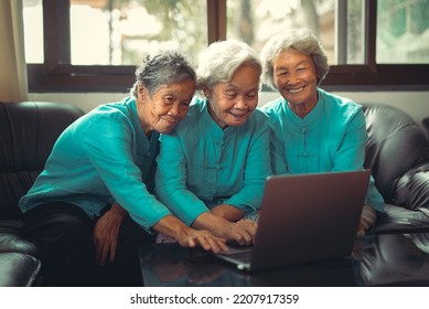 Three Older Asian Woman Sitting On Sofa Using Laptop Teleconference With Family. 