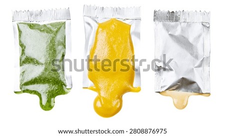 Three open foil condiment packets with green herb sauce mustard and mayonnaise