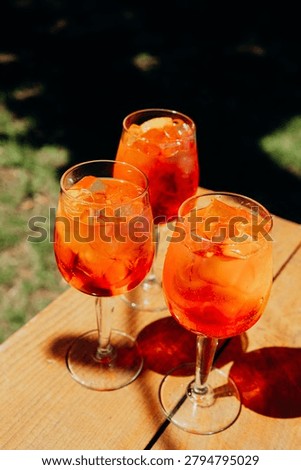Three orange drinks with ice sit on a wooden table.