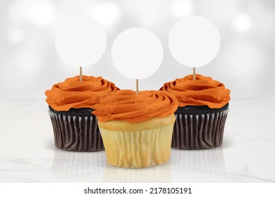 Three orange frosted cupcakes in a minimalistic kitchen scene. Will they be a treat or a trick this Halloween? - Shutterstock ID 2178105191
