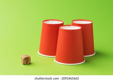 Three Orange Paper Cups And One Wooden Cube With A Question Mark Symbol, The Concept Of Gambling And Its Harm