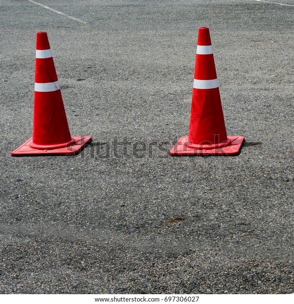 Three orange\
plastic cones on the asphalt\
road