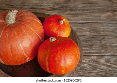Three orange pumpkins on a rustic wooden background. Top view