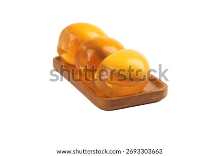 Three oversized yellow mutant tomatoes with unusual egg-like shape arranged on wooden serving board, isolated on white background. Fresh organic heirloom vegetables with glossy skin.