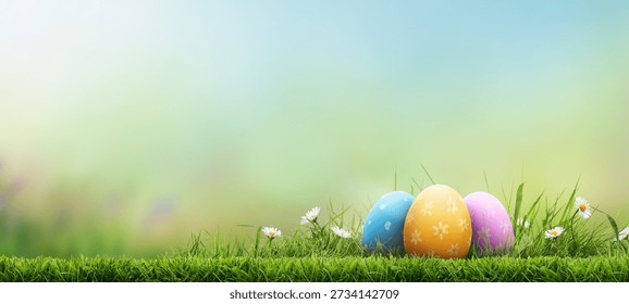 Three painted easter eggs celebrating a Happy Easter on a spring day with a green grass meadow, bright sunlight and a fresh spring background with copy space.
