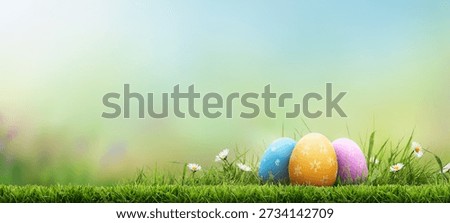 Three painted easter eggs celebrating a Happy Easter on a spring day with a green grass meadow, bright sunlight and a fresh spring background with copy space.