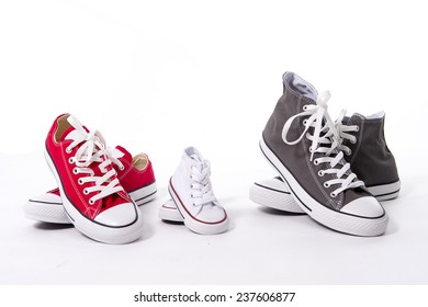 three pair of casual shoes in father big, mother medium and son or daughter small kid size representing family, growth, education and togetherness concept isolated on white background