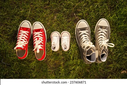 three pair of shoes in father big, mother medium and son or daughter small kid size in grass park with Autumn leaves representing family, growth, education and togetherness concept 