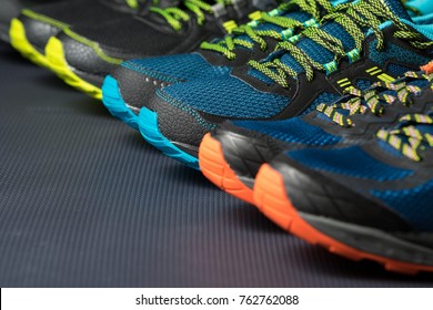 Three Pairs Of Colorful Running Trainers / Exercise Shoes On The Floor Of A Sport / Shoe Shop. Potential Copy Space On Floor.