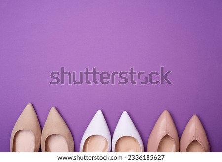 Three pairs of elegant female pointed-toe classic shoes on the purple background. Flat lay, top view, copy space for text. Advertising poster