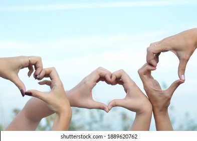 Three Pairs Of Hands Make A Heart Shape Against The Sky