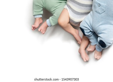 Three Pairs Of Legs Of Newborn Babies Triplets. Twins Brothers. Isolate. Copy Space 