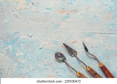 three palette knifes on artist canvas with coating of oil paint - Powered by Shutterstock