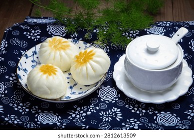 Three pan fried buns on blue and white porcelain plate tea chopsticks dark cloth