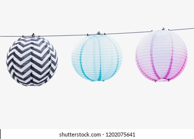 Three paper lanterns on a string - soft blue, pink and patterned black and white. High key photo. White background - Powered by Shutterstock