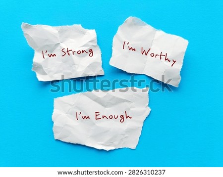 Three paper notes on blue background with handwritten text I AM STRONG, I AM WORTHY, I AM ENOUGH - powerful self talk positive affirmations to boost self confidence in daily life