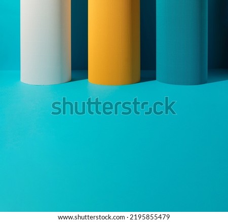 Three paper pillars - white, yellow and blue on blue background with copy space.