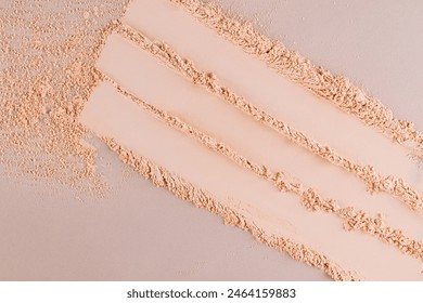 Three parallel stripes of a delicate texture of decorative face powder in a natural tone on a beige background. View from above. Swatch powder