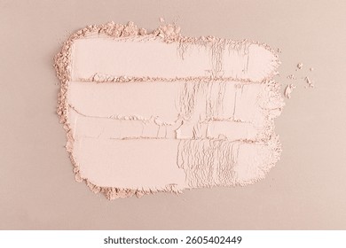 Three parallel strokes of compact dry powder in a natural tone on a beige background. Delicate powder texture. A sample for an advertising layout
