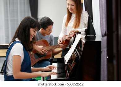 Three People Asian Family, Mother Son And Daughter Playing Music Together. Piano, Guitar And Ukulele In Family Band At Home