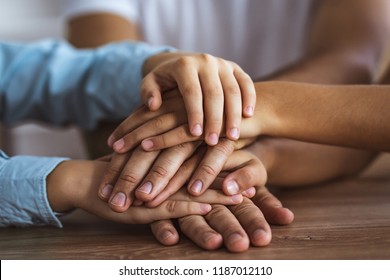 The three people hold hands together at the table - Shutterstock ID 1187012110