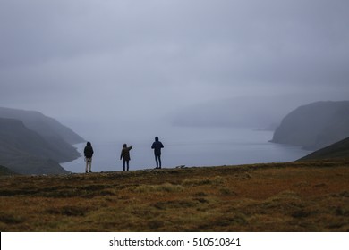 Three People Looking To The Amazing View Of Norwegian Fjord At Rainy Weather