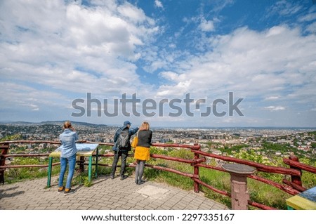 Three people looking at the skyline of Buda and Pest from the Sas Hill viewpoint on a sunny day, Budapest