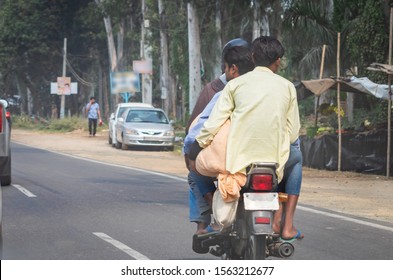 three people on a bike without helmet  breaking traffic rules in India  on a highway 