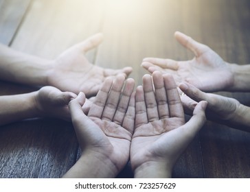 Three People Pray And Praising God Together Over Wooden Table With The Light From Above, Copy Space.