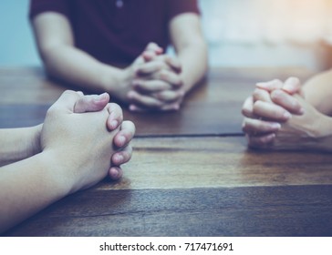 Three People Are Praying Together On Wooden Table 