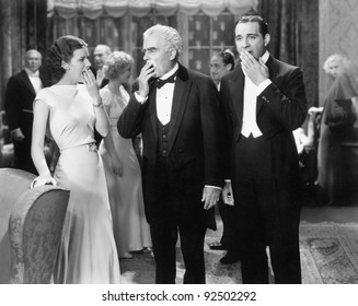 Three People Standing Together At A Formal Party Yawning And Being Bored