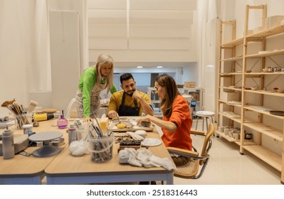 Three people, two women and a man, working together on a pottery project in a creative studio setting. - Powered by Shutterstock