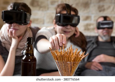 three people with virtual reality glasses and snacks, having fun