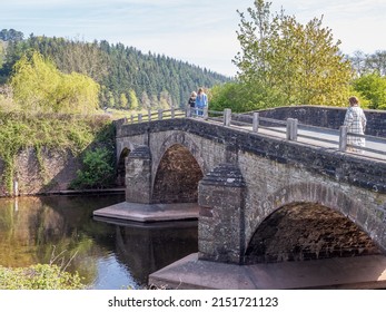 three people  walking across a three arch medieval stone bridge in the United Kingdom 