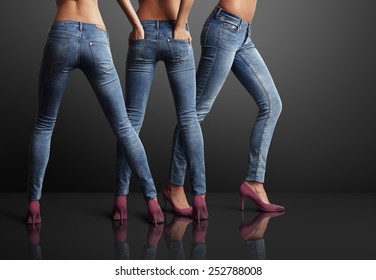 three perfect shaped woman in a dark room, wearing jeans
