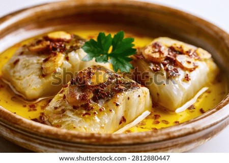 Three perfectly cooked cod fillets bathed in a rich garlic butter sauce, garnished with herbs and spices.