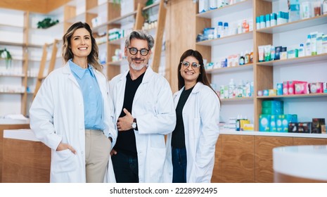 Three pharmacists standing together and looking at the camera in a drug store. Group of healthcare professionals working in a pharmacy. - Powered by Shutterstock