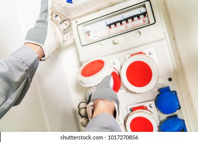 Three Phase Electric Power Supply. Worker Attaching Machine Cord To The Outlet.